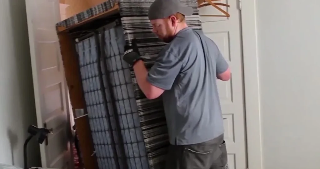 Mover tipping a striped sofa on end to fit it through a bedroom doorway
